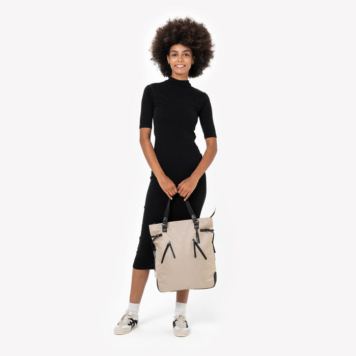Woman holding a Sherpani Tempest Straw Beige Convertible Tote by straps against white background. #color_straw