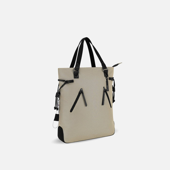 A Sherpani Tempest Straw Beige Convertible Tote, 3/4 view showing lockable pockets & straps against white background. #color_straw