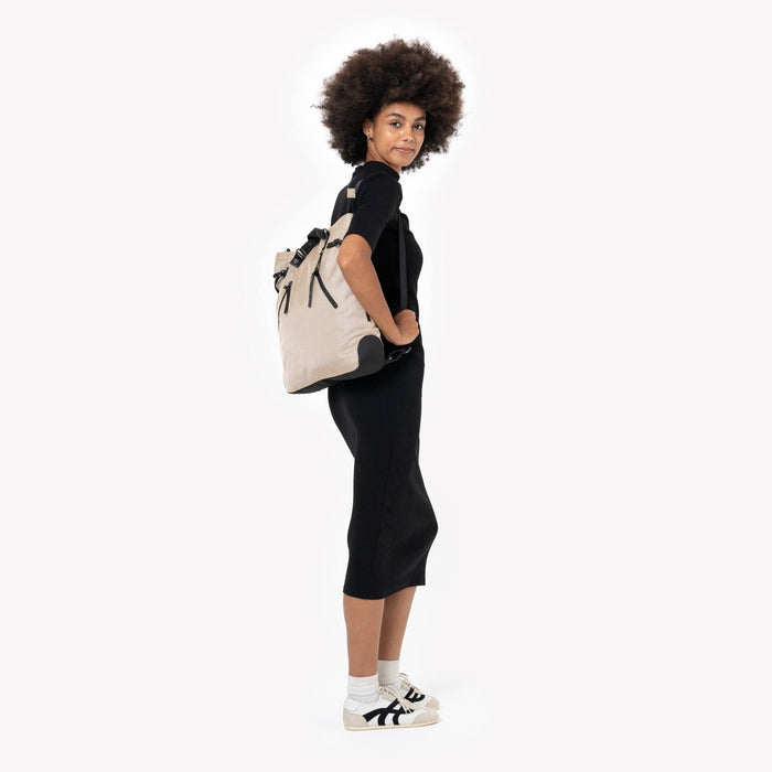 Woman wearing a Sherpani Tempest Straw Beige Convertible Tote on her back against white background. #color_straw