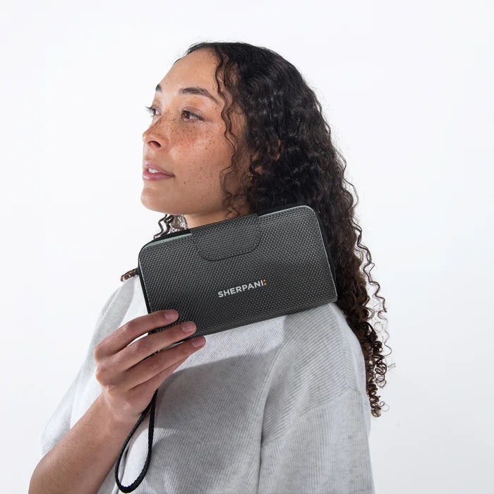 Woman holding a Sherpani Tulum Granite Anti-Theft Wallet against white background. #color_granite-grey