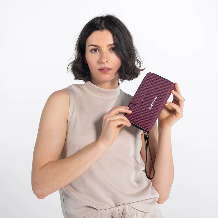 Woman holding a Sherpani Tulum Smoky Orchid Anti-Theft Wallet against white background. #color_smoky-orchid-pink
