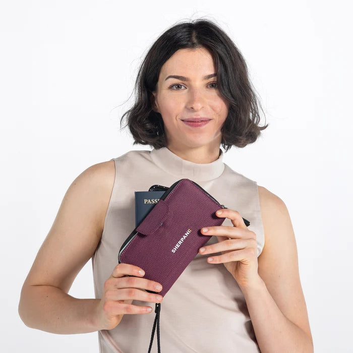 Woman holding a Sherpani Tulum Smoky Orchid Anti-Theft Wallet against white background.  #color_smoky-orchid-pink