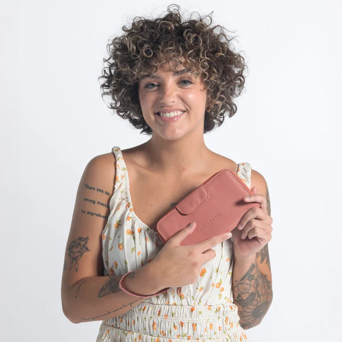 Woman holding a Sherpani Tulum Desert Pink RFID Wallet against white background.   #color_desert-pink