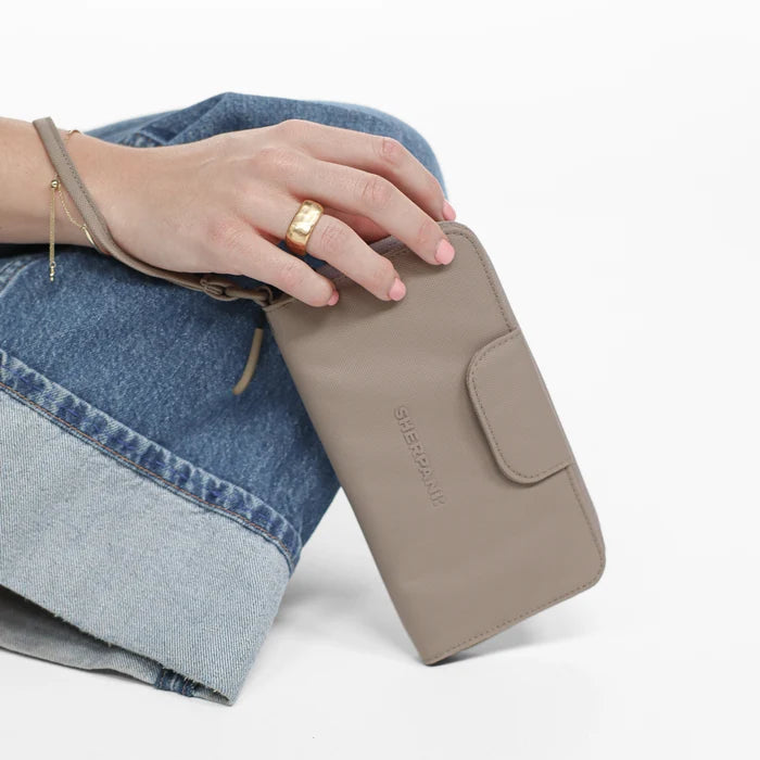 Woman holding a Sherpani Tulum Dune RFID Wallet against white background.  #color_dune-tan