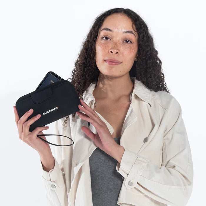 Woman holding a Sherpani Tulum Raven Black RFID Wallet against white background.   #color_raven-black