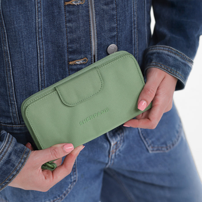 Woman holding a Sherpani Tulum Olivine RFID Wallet against white background.  #color_olivine-green
