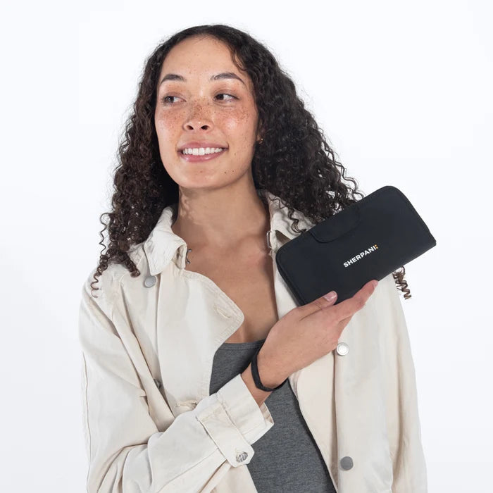Woman holding a Sherpani Tulum Raven Black RFID Wallet against white background.   #color_raven-black