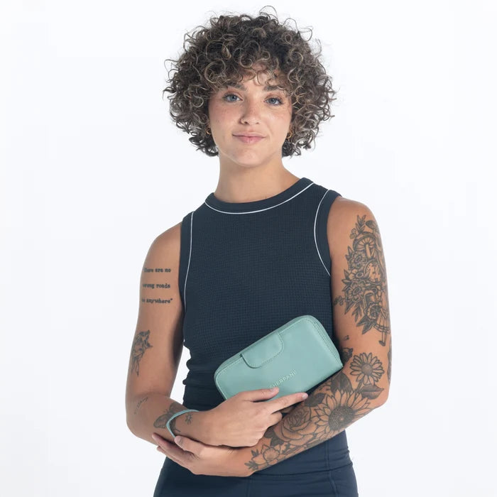 Woman holding a Sherpani Tulum Surf Blue RFID Wallet against white background.   #color_surf-blue