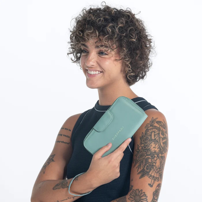 Woman holding a Sherpani Tulum Surf Blue RFID Wallet against white background.   #color_surf-blue