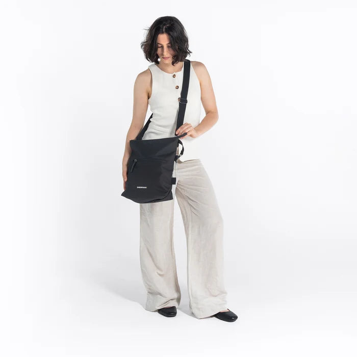 Woman wearing a Sherpani Vale Carbon Black Anti-theft Reversible Crossbody against white background. #color_carbon-black