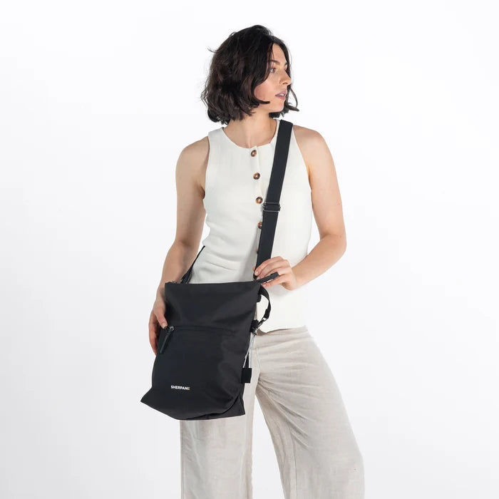 Woman wearing a Sherpani Vale Carbon Black Anti-theft Reversible Crossbody against white background. #color_carbon-black