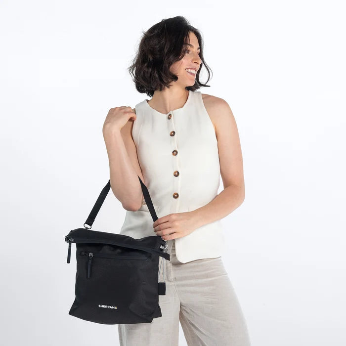Woman wearing a Sherpani Vale Carbon Black Anti-theft Reversible Crossbody against white background. #color_carbon-black