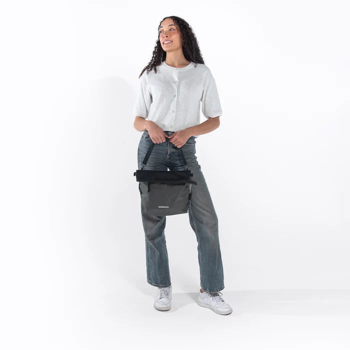 Woman wearing a Sherpani Vale Granite Anti-theft Reversible Crossbody against white background. #color_granite-grey