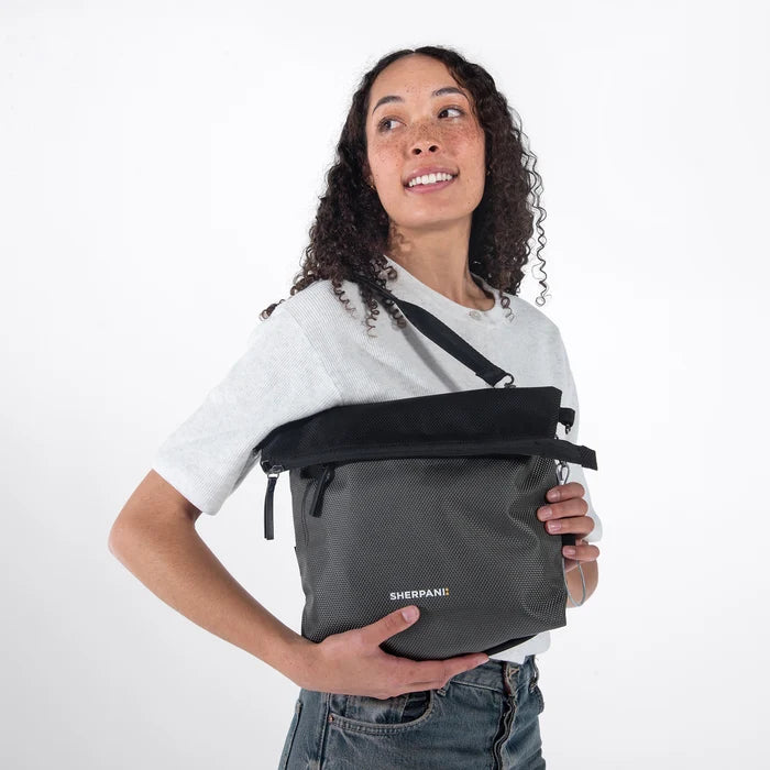 Woman wearing a Sherpani Vale Granite Anti-theft Reversible Crossbody against white background. #color_granite-grey