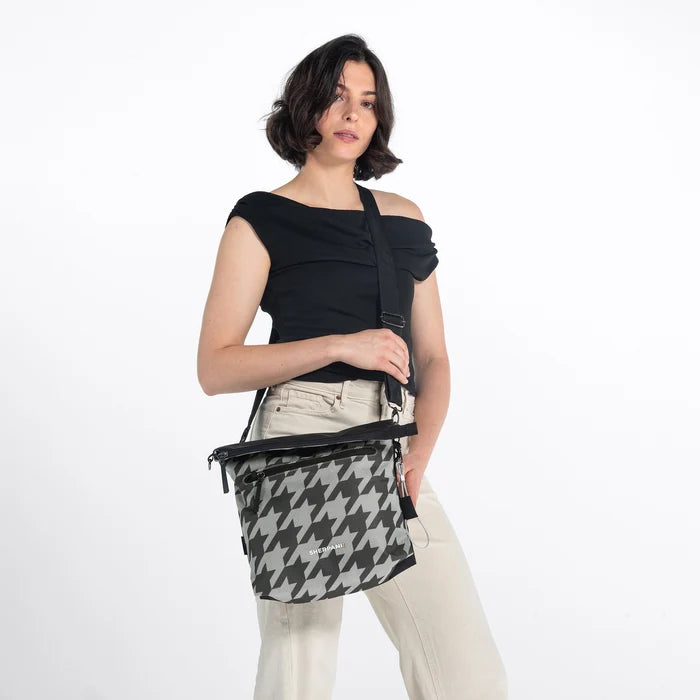 Woman wearing a Sherpani Vale Houndstooth Anti-theft Reversible Crossbody against white background. #color_houndstooth-print