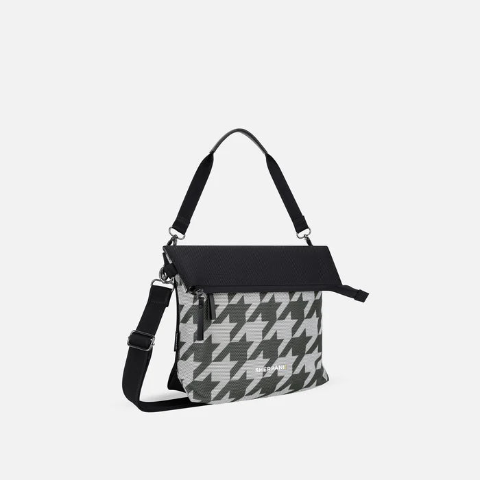 A Sherpani Vale Houndstooth Anti-theft Reversible Crossbody, 3/4 view showing folded over front on white background.  #color_houndstooth-print