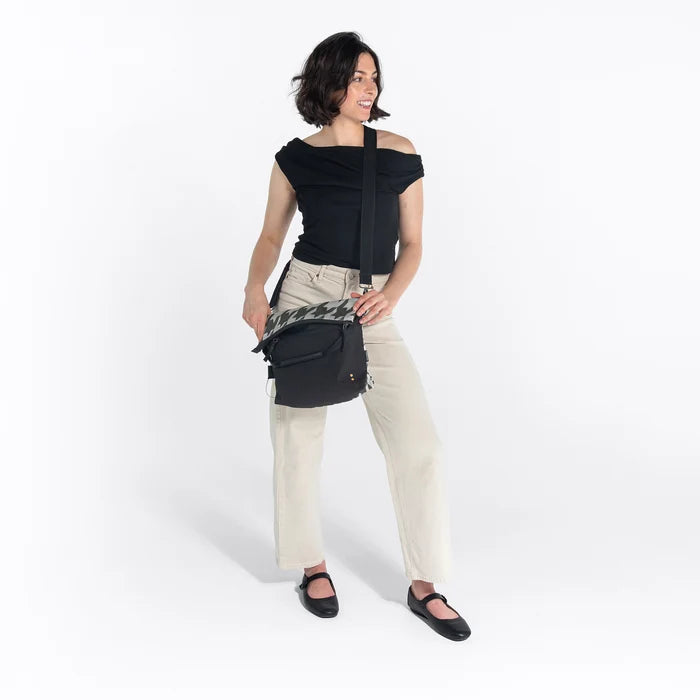 Woman wearing a Sherpani Vale Houndstooth Anti-theft Reversible Crossbody against white background. #color_houndstooth-print