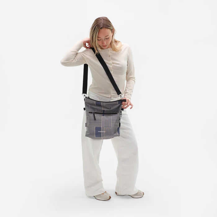 Woman wearing a Sherpani Vale Passport Anti-theft Reversible Crossbody against white background. #color_passport-print