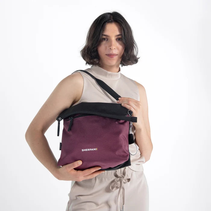 Woman wearing a Sherpani Vale Smoky Orchid Anti-theft Reversible Crossbody against white background. #color_smoky-orchid-pink