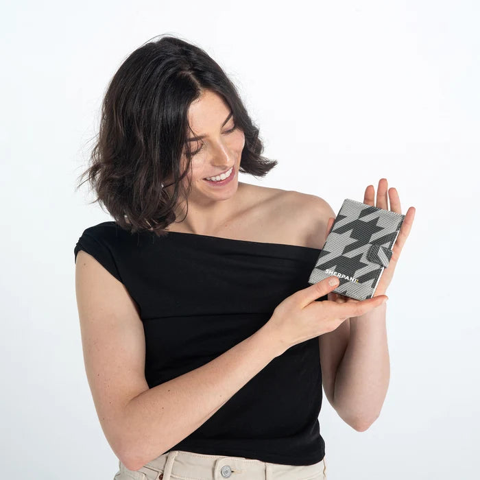 Woman holding a Sherpani Vienna Houndstooth Anti-theft Passport Wallet against white background. #color_houndstooth-print