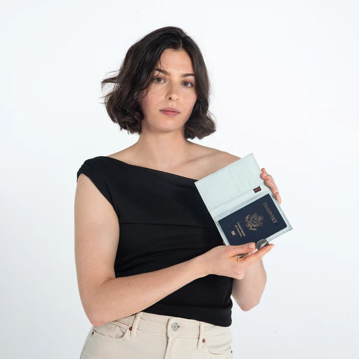Woman showing inside of Sherpani Vienna Houndstooth Anti-theft Passport Wallet with passport & cards against white background. #color_houndstooth-print