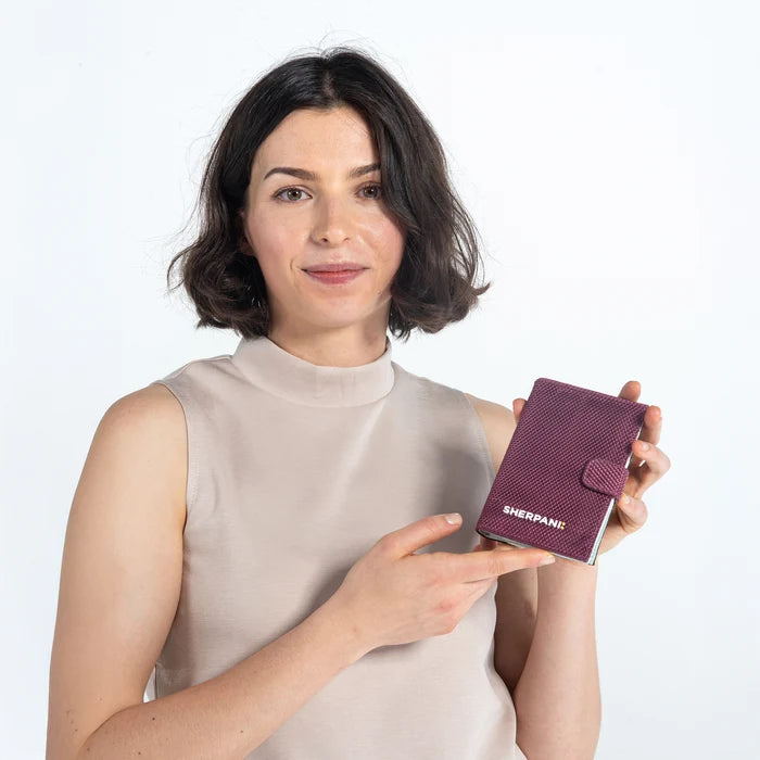 Woman holding a Sherpani Vienna Smoky Orchid Anti-theft Passport Wallet against white background. #color_smoky-orchid-pink