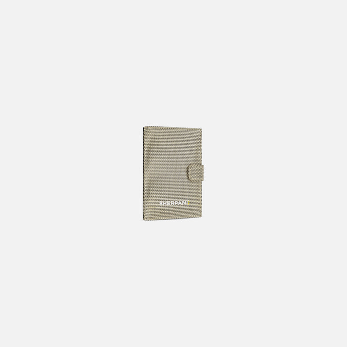 A Sherpani Vienna Straw Beige Anti-theft Passport Wallet, 3/4 view against white background.#color_straw-beige
