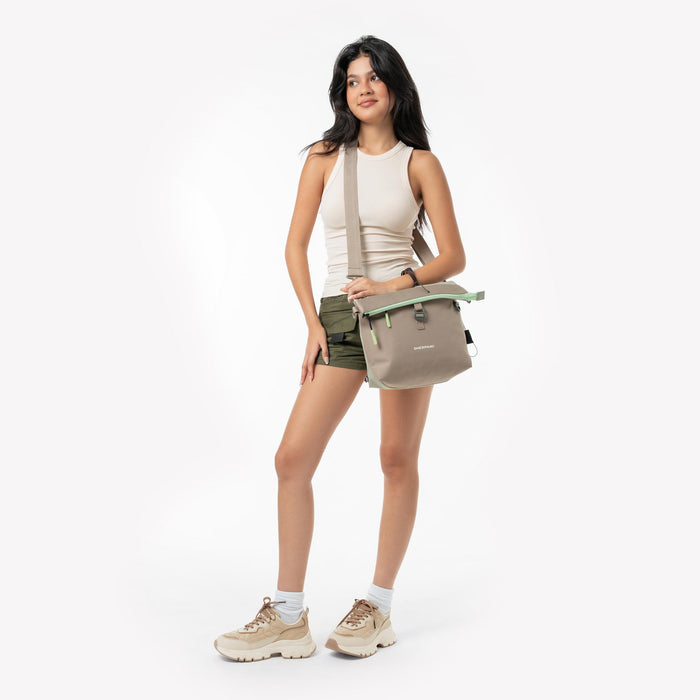 Woman wearing a Sherpani Viso Desert Aloe Foldover Bag against a white backdrop. #color_desert-aloe