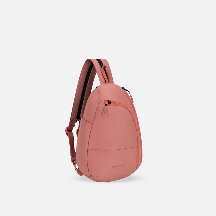 A Sherpani Wayfarer Desert Pink Convertible Sling, 3/4 view showing lockable pockets and main strap on white background. #color_desert-pink