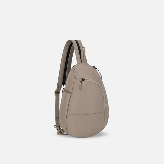 A Sherpani Wayfarer Dune Convertible Sling, 3/4 view showing lockable pockets and main strap on white background. #color_dune-tan