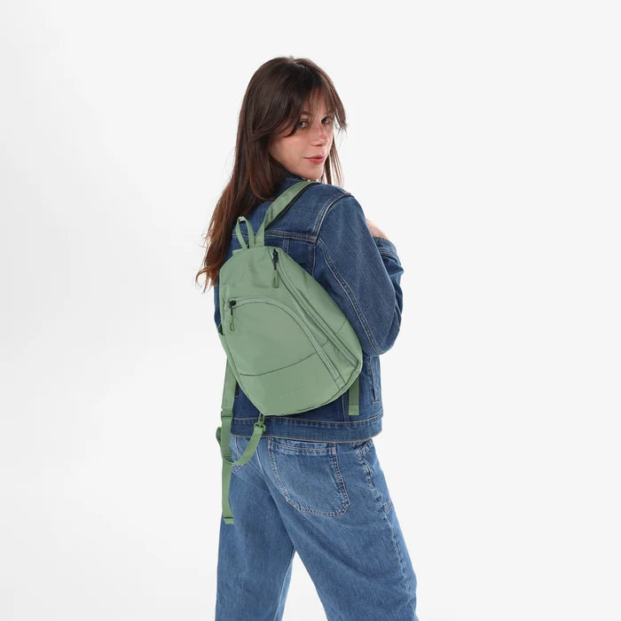 A woman wearing a Sherpani Wayfarer Olivine Convertible Sling on her back against white background.  #color_olivine-green