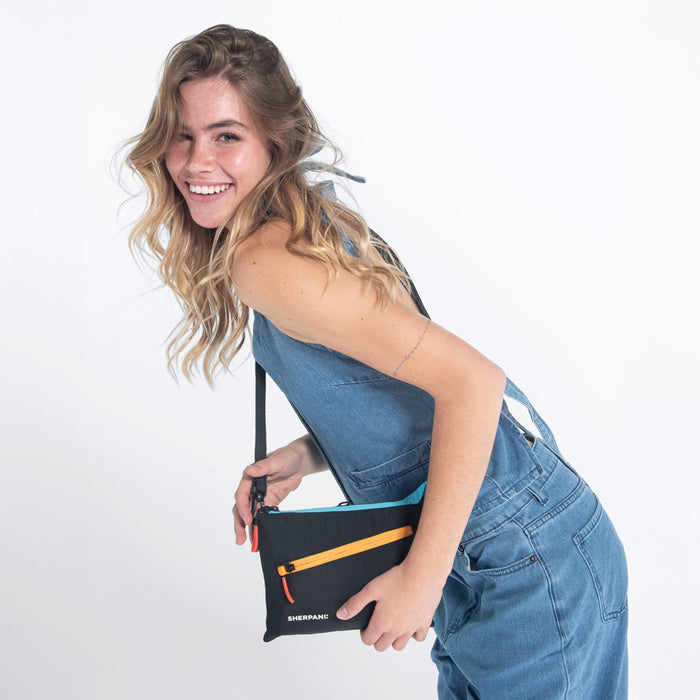 Woman wearing a Sherpani Zoom Chromatic Black Slim RFID Crossbody against white background. #color_chromatic-black