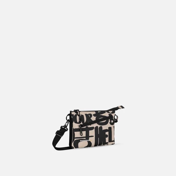 A Sherpani Zoom Ciao Slim RFID Crossbody, 3/4 view showing lockable pocket and two main pockets on white background. #color_ciao-print