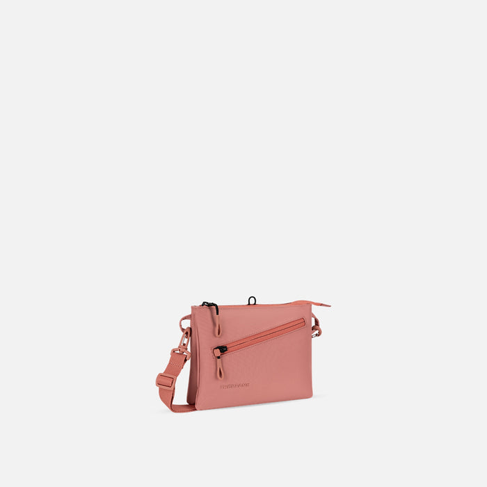 A Sherpani Zoom Desert Pink Slim RFID Crossbody, 3/4 view showing lockable pocket and two main pockets on white background. #color_desert-pink