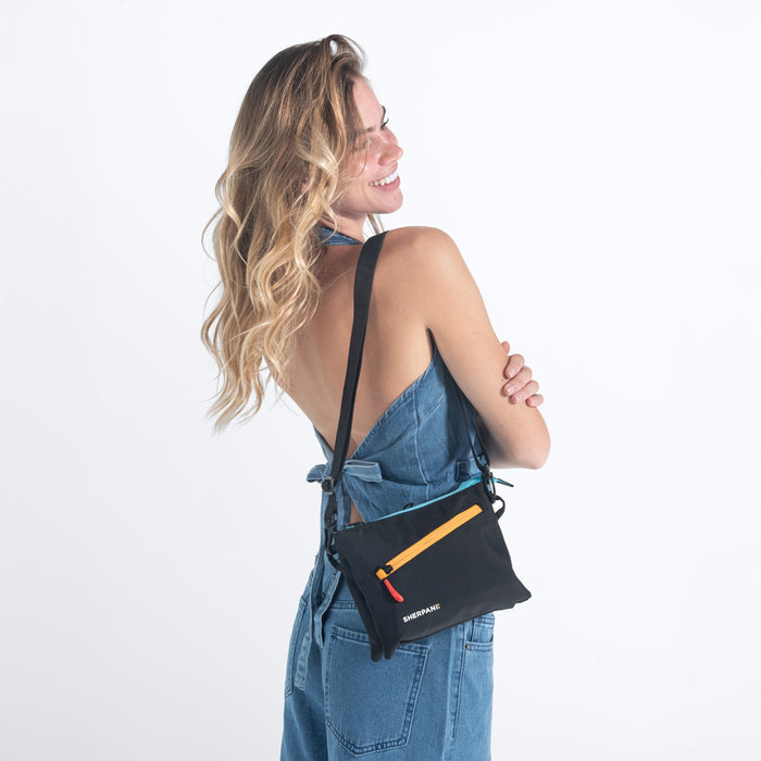 Woman wearing a Sherpani Zoom Chromatic Black Slim RFID Crossbody against white background. #color_chromatic-black