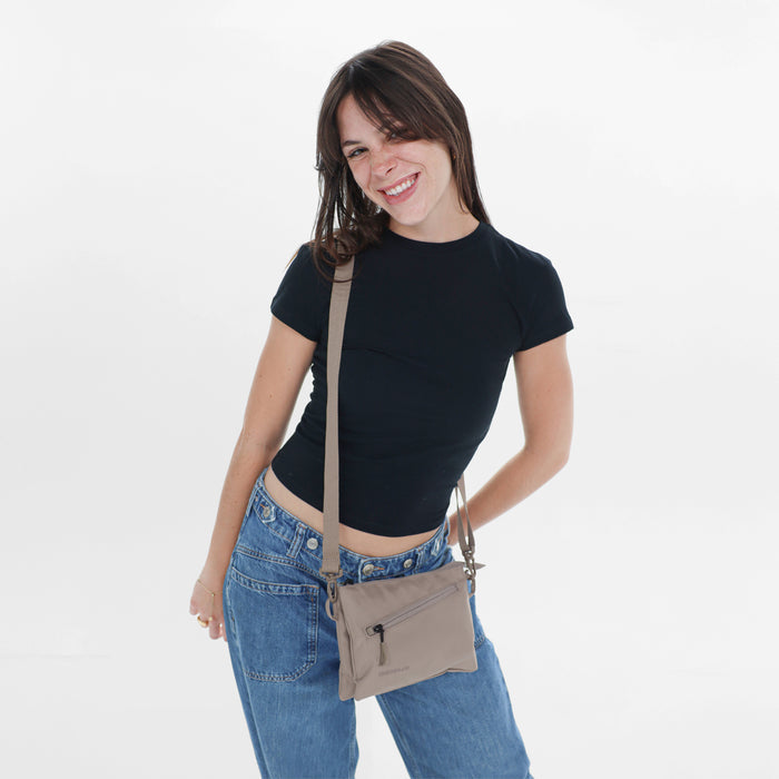 Woman wearing a Sherpani Zoom Dune Slim RFID Crossbody against white background. #color_dune-tan