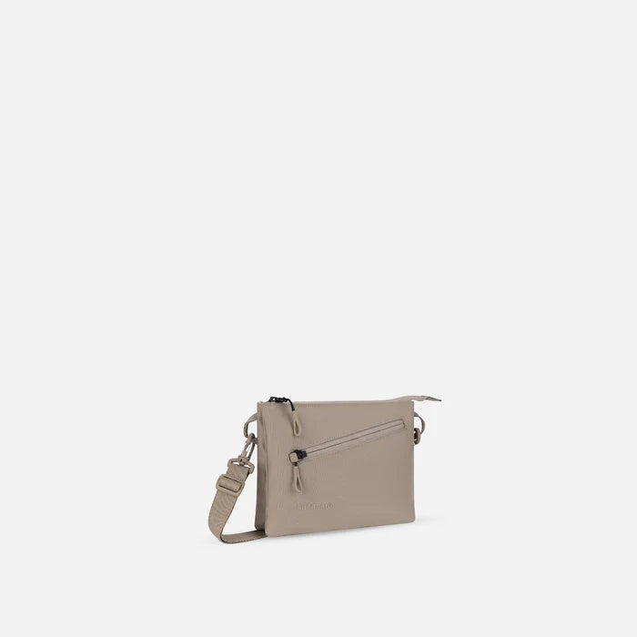 A Sherpani Zoom Dune Slim RFID Crossbody, 3/4 view showing lockable pocket and two main pockets on white background. #color_dune-tan