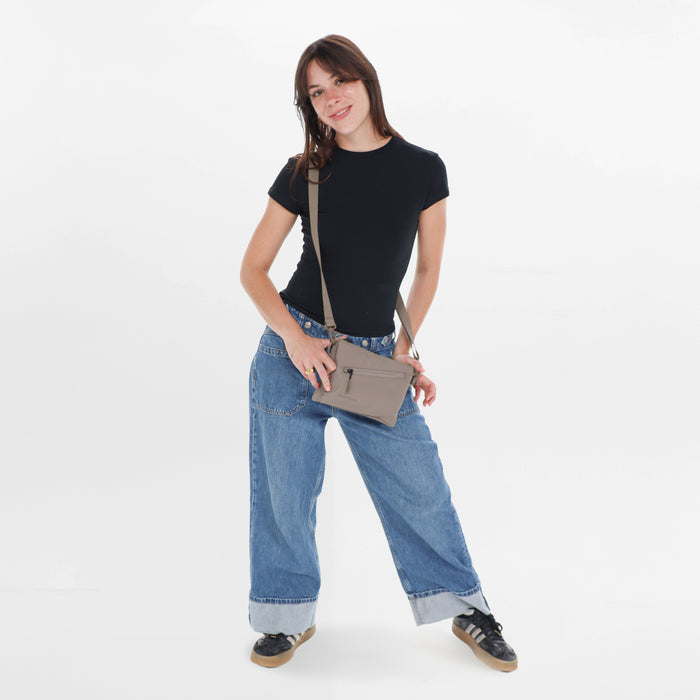 Woman wearing a Sherpani Zoom Dune Slim RFID Crossbody against white background. #color_dune-tan