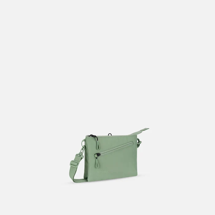 A Sherpani Zoom Olivine Slim RFID Crossbody, 3/4 view showing lockable pocket and two main pockets on white background. #color_olivine-green