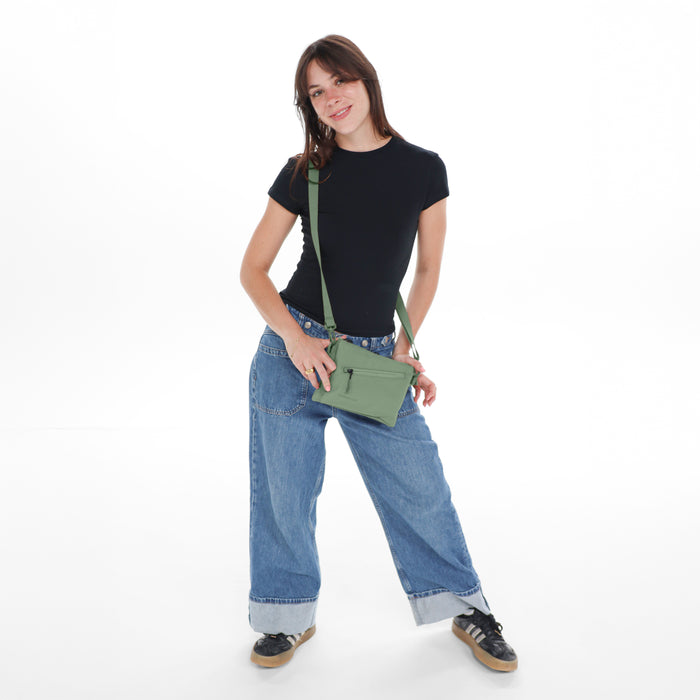 Woman wearing a Sherpani Zoom Oiivne Slim RFID Crossbody against white background. #color_olivine-green