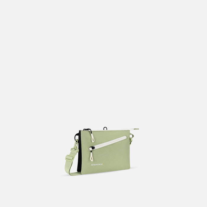 A Sherpani Zoom Palm Green Slim RFID Crossbody, 3/4 view showing lockable pocket and two main pockets on white background. #color_palm-green