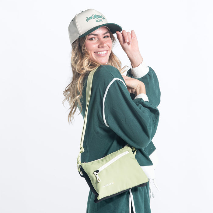 Woman wearing a Sherpani Zoom Palm Green Slim RFID Crossbody against white background. #color_palm-green