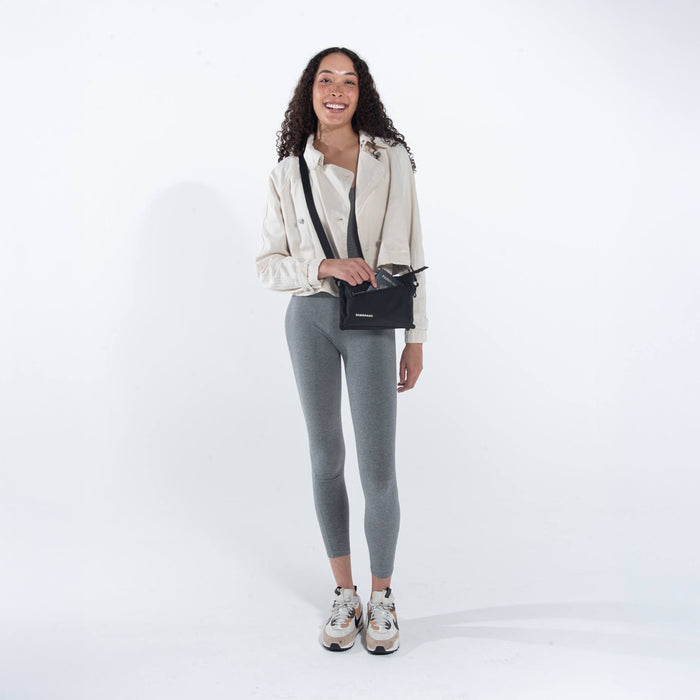 Woman wearing a Sherpani Zoom Raven Black Slim RFID Crossbody against white background. #color_raven-black