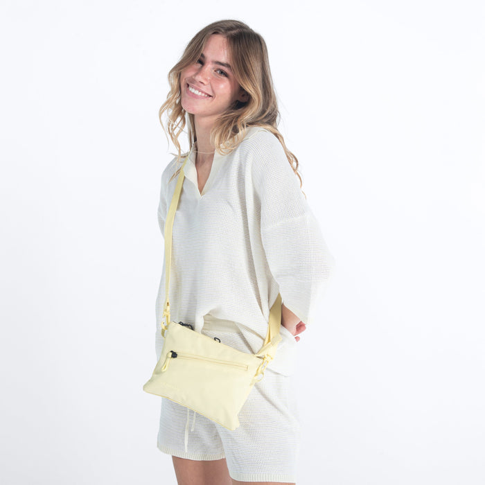 Woman wearing a Sherpani Zoom Sol Yellow Slim RFID Crossbody against white background. #color_sol-yellow