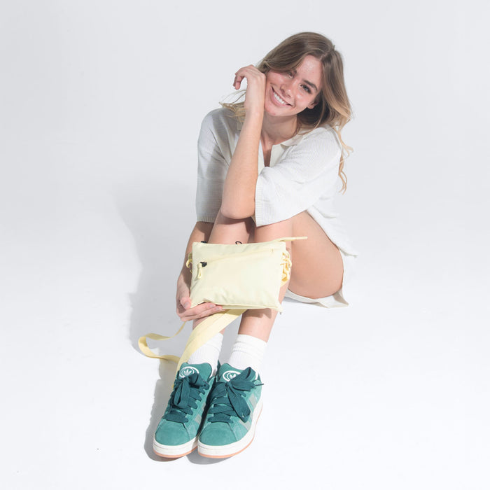 Woman wearing a Sherpani Zoom Sol Yellow Slim RFID Crossbody against white background. #color_sol-yellow