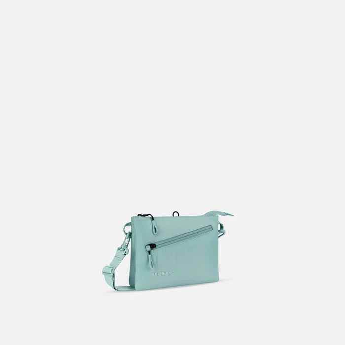 A Sherpani Zoom Surf Blue Slim RFID Crossbody, 3/4 view showing lockable pocket and two main pockets on white background. #color_surf-blue